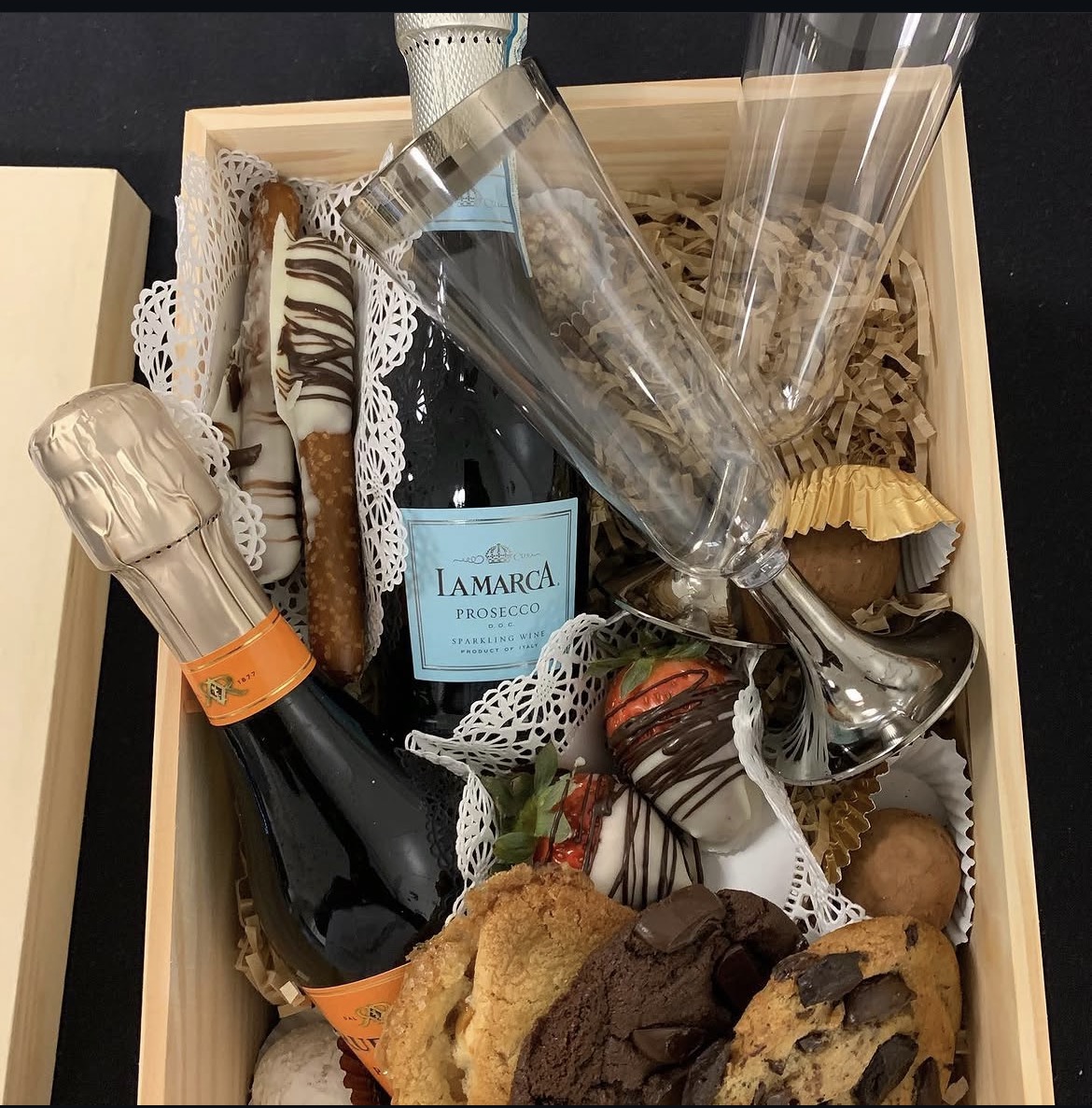 Gift box with sparkling wine, flutes, chocolate-dipped strawberries and assorted sweet treats