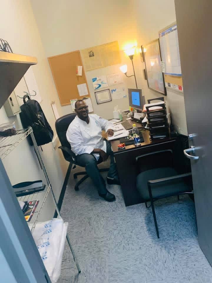 Chef Jarrel McRae in a white chef coat seated at his office desk
